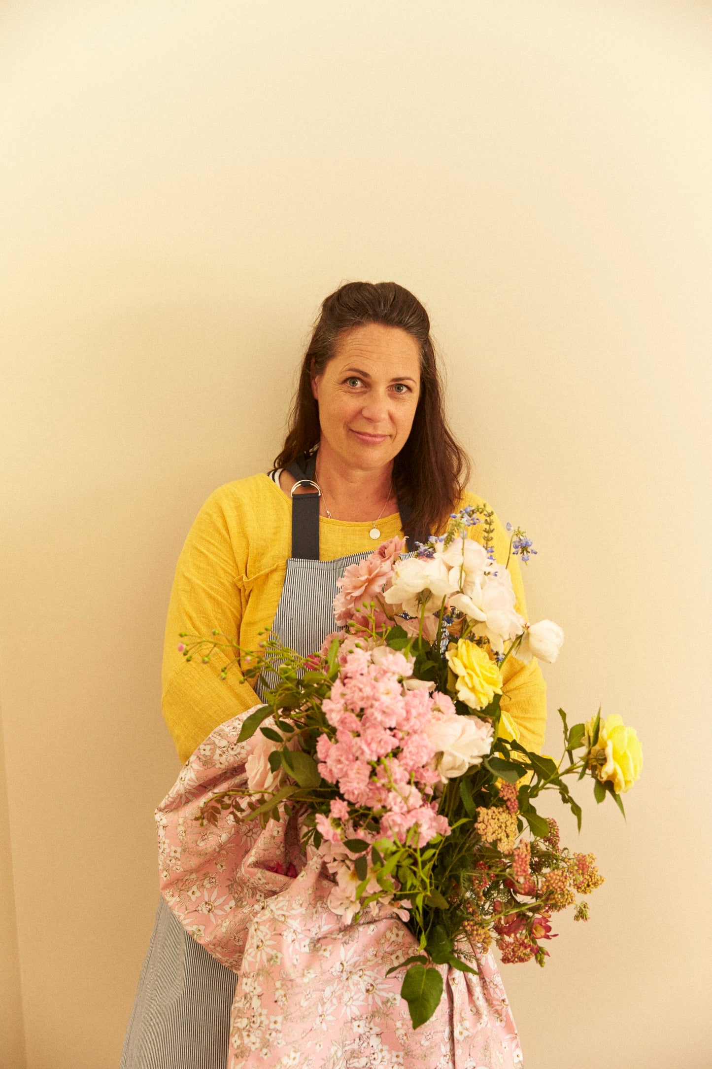 Woman holding a bouquet of flowers against a plain background