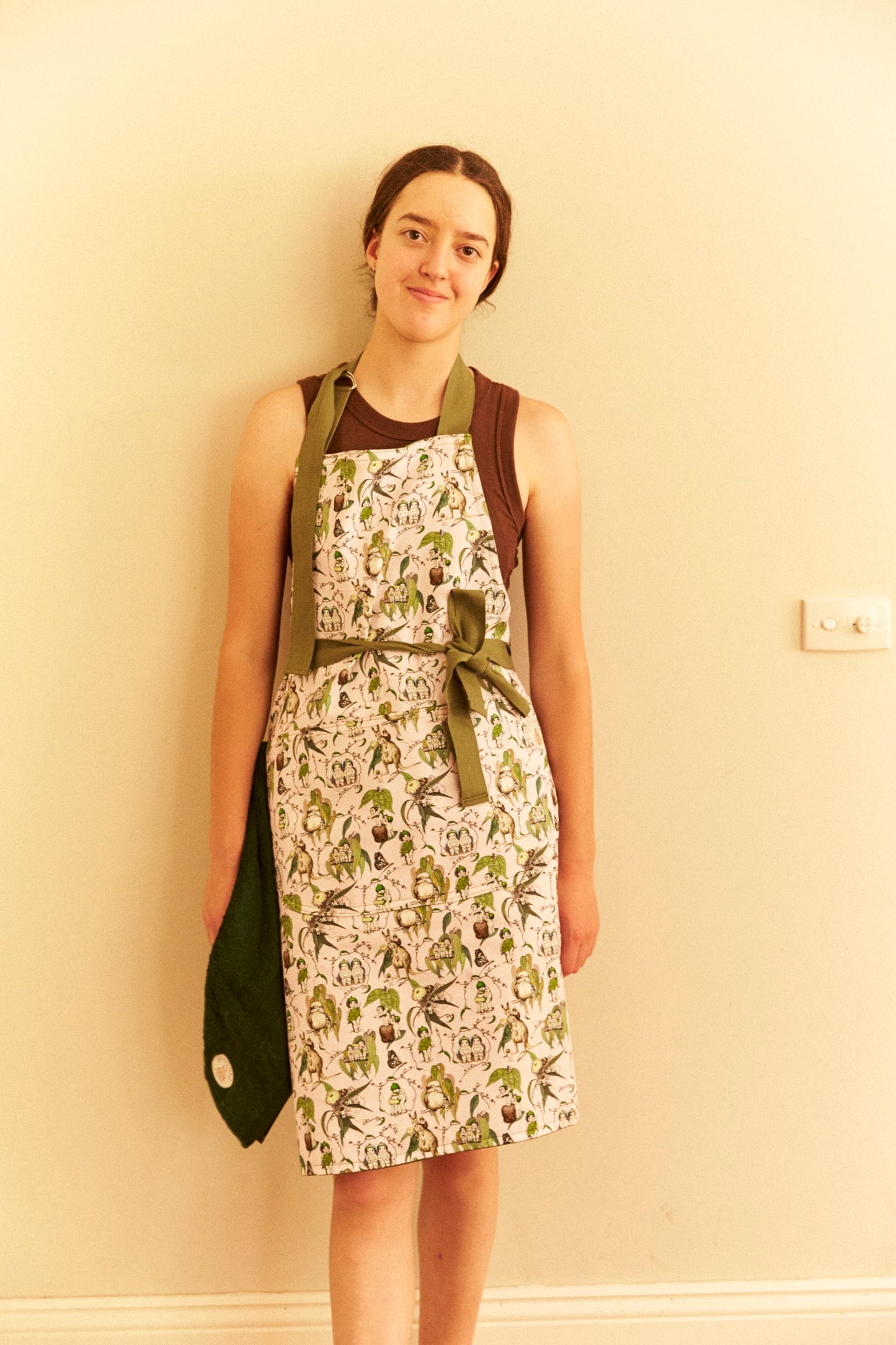 Woman wearing a patterned apron against a beige wall