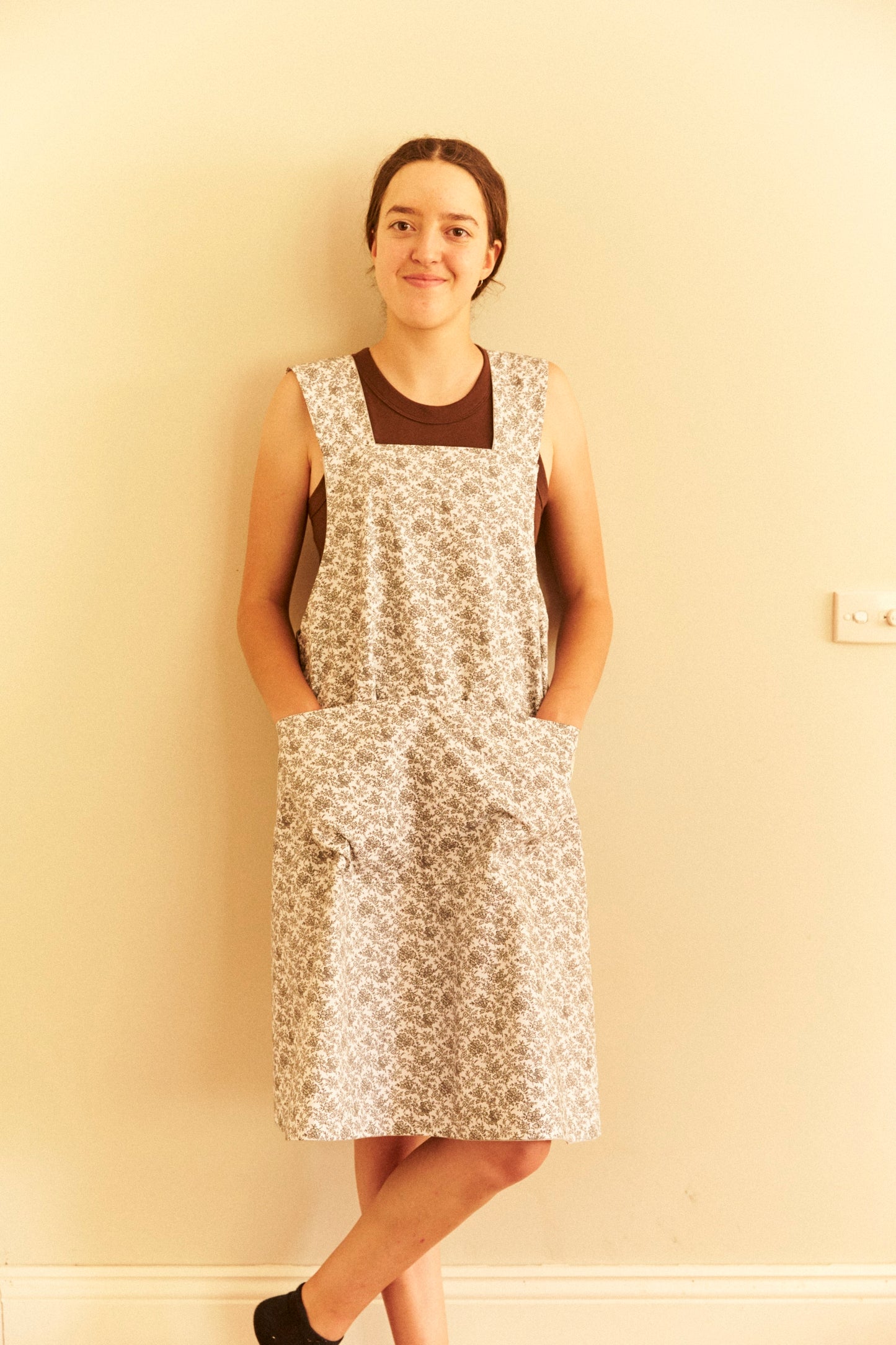 Woman wearing a floral dress against a plain wall