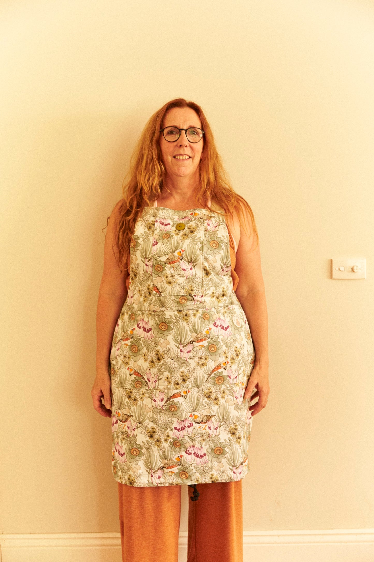 Woman wearing a floral dress against a plain wall.