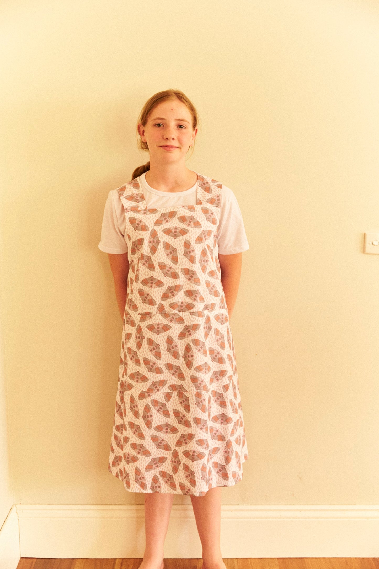 Person wearing a patterned dress against a plain wall