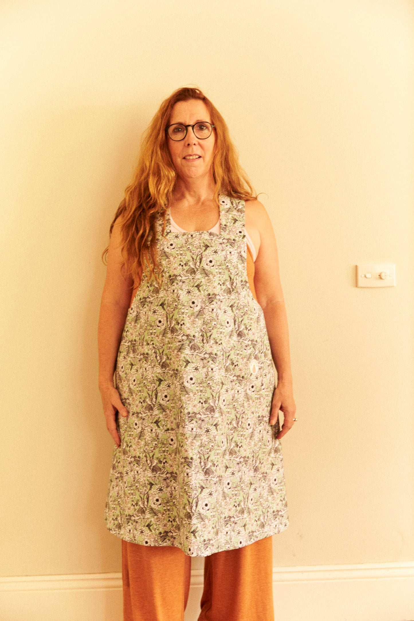 Woman wearing a floral dress against a plain wall