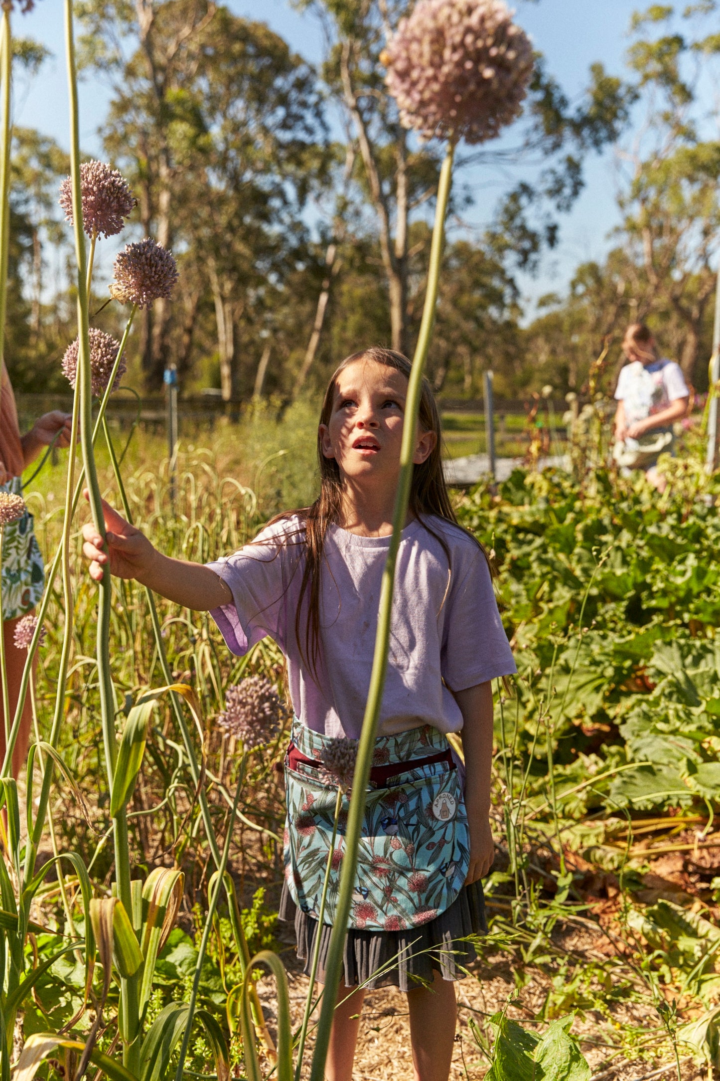 Child in a garden holding a tall plant with large flowers