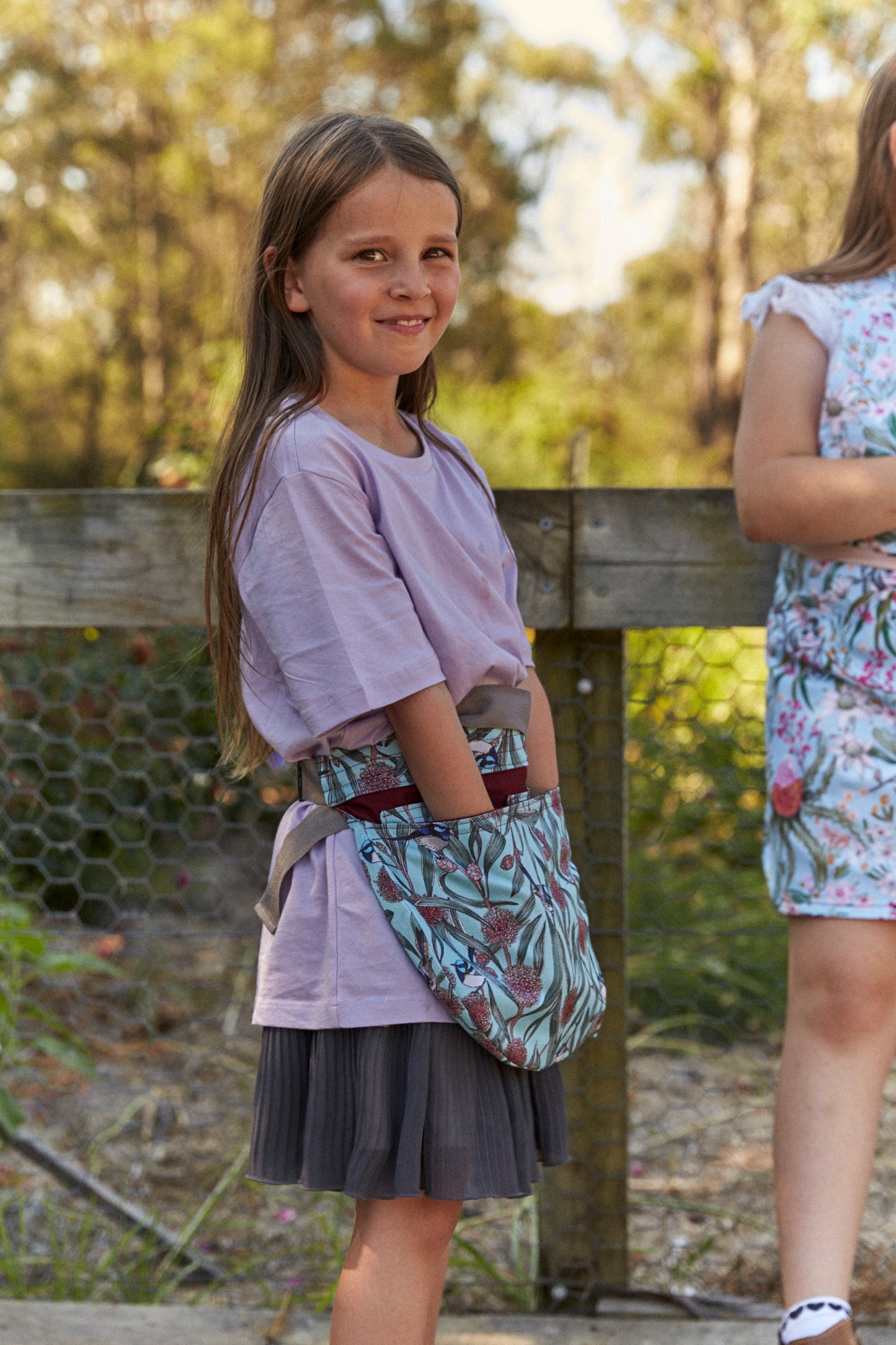 Young girl wearing a patterned bag outdoors with blurred background