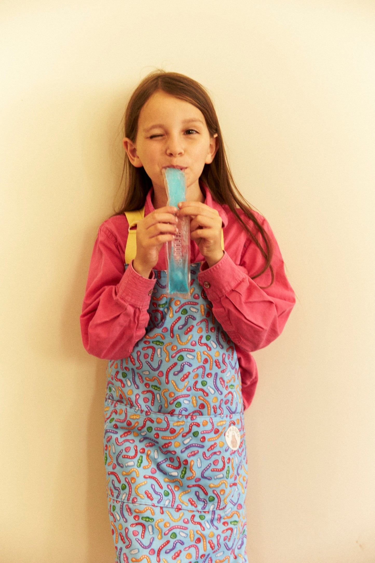 Girl in colorful outfit holding a blue object against a plain background