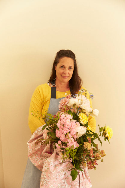 Woman holding a bouquet of flowers against a plain background