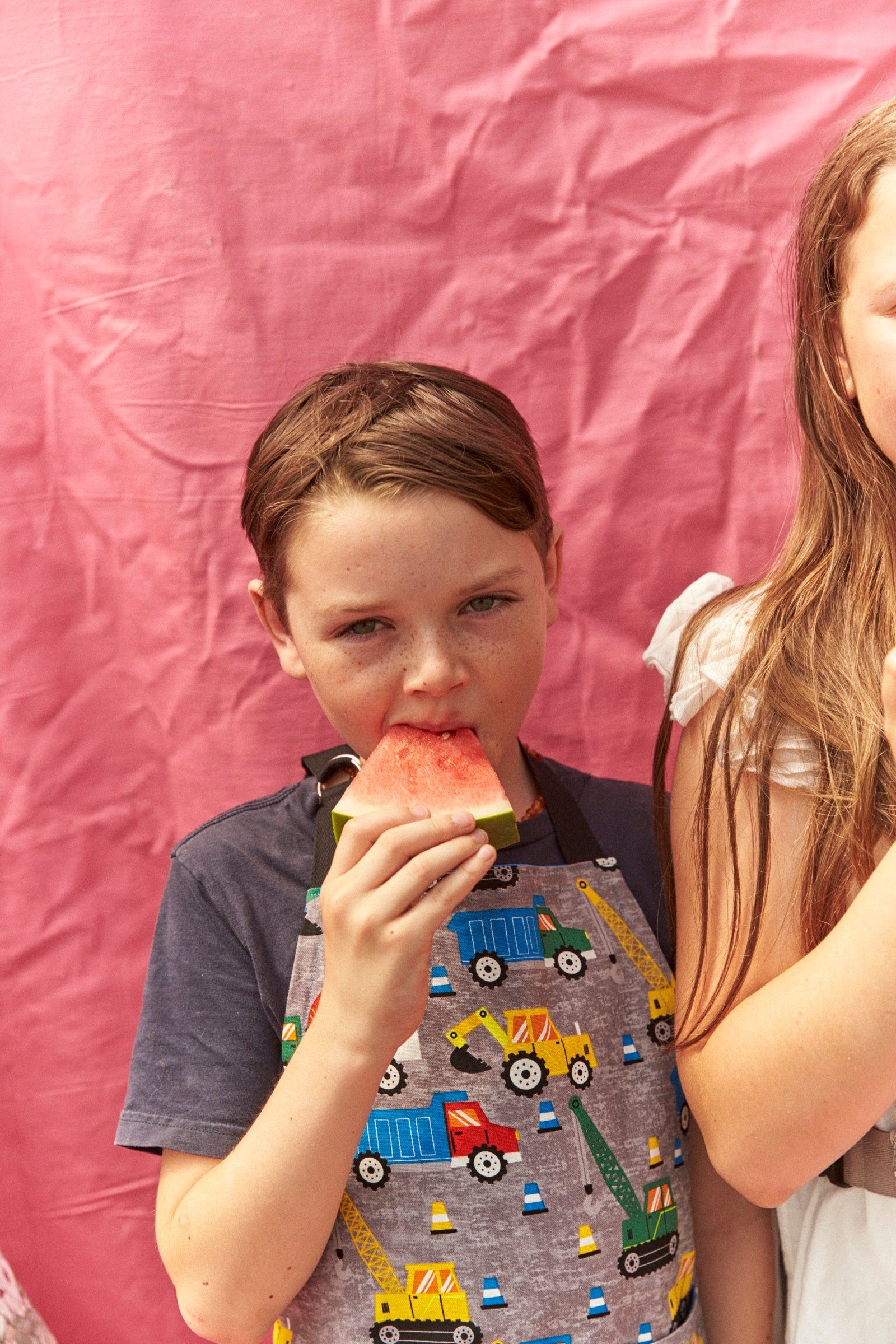 Child eating watermelon with a pink background