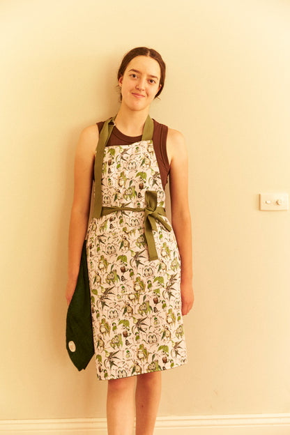 Woman wearing a patterned apron against a beige wall